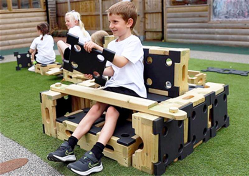 Child sat in a Play Builder car imagining to drive a car which he has built using the blocks